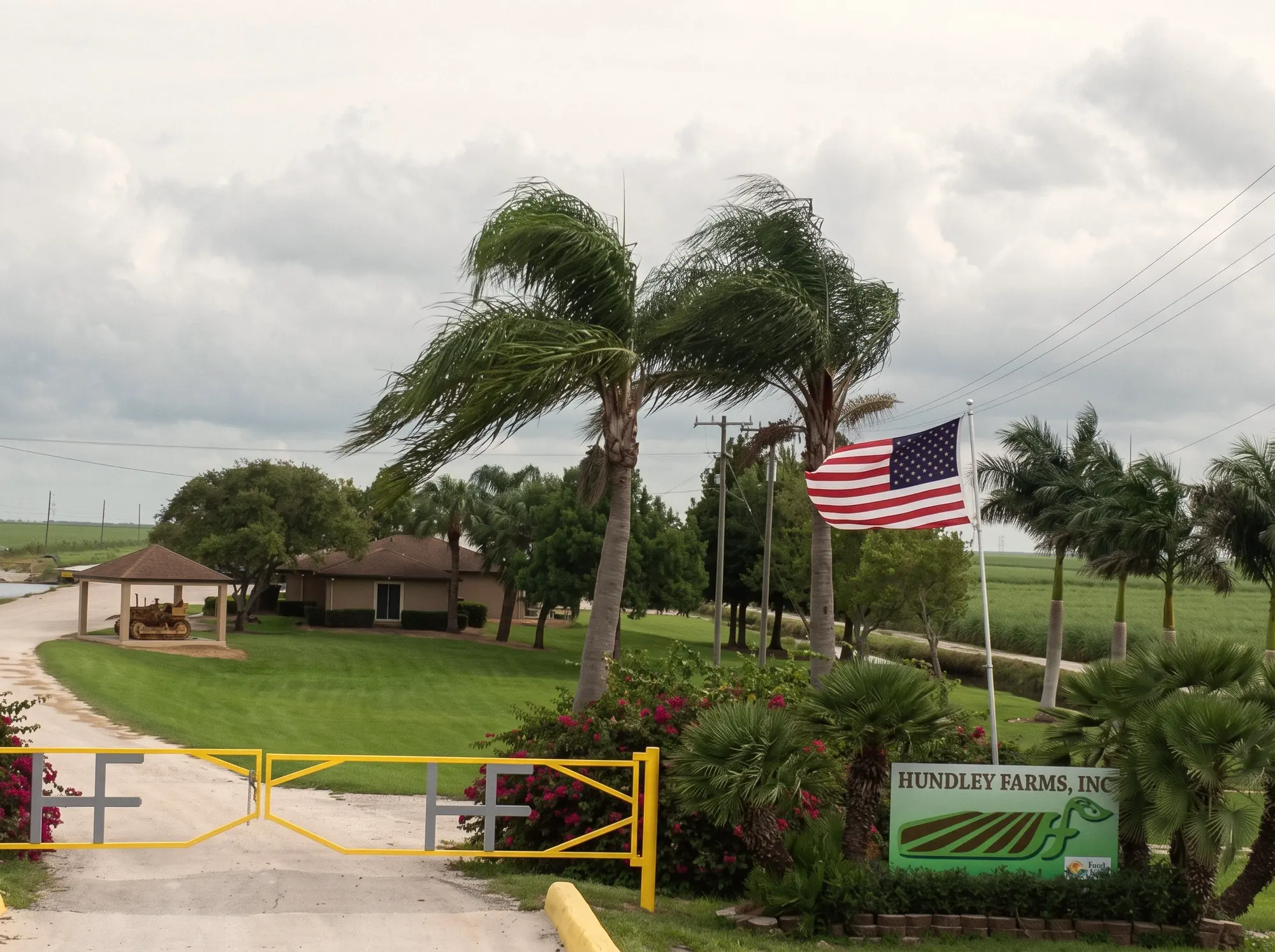 The Hundley Farms entrance gate with the HF monogram, palm trees, and an American flag