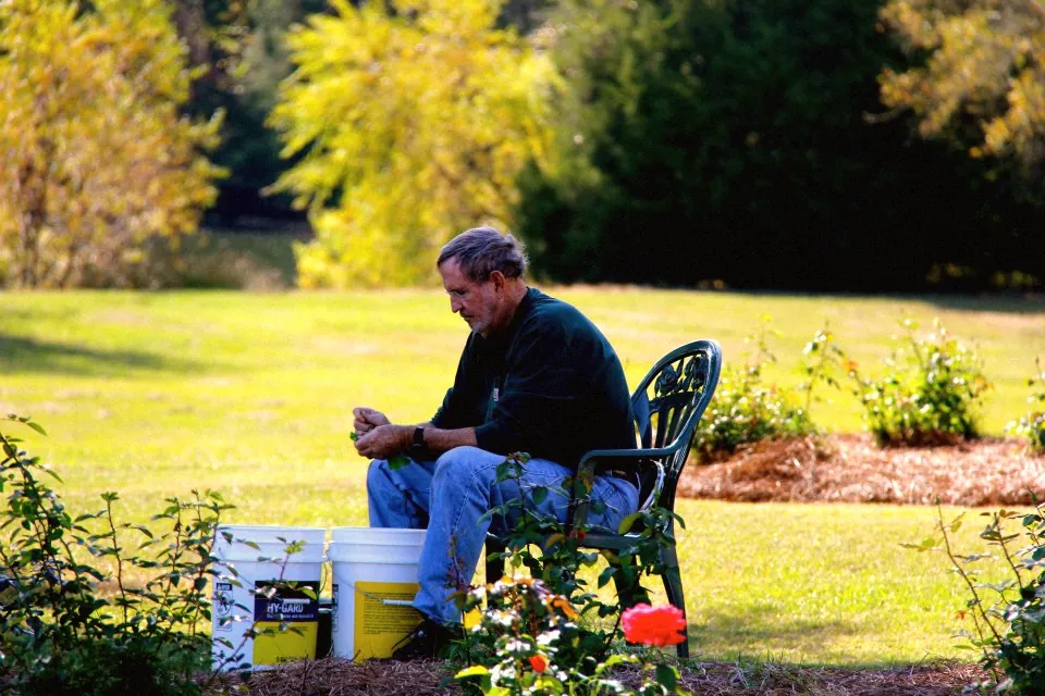 John L. Hundley seated outdoors, shelling peas into a bucket